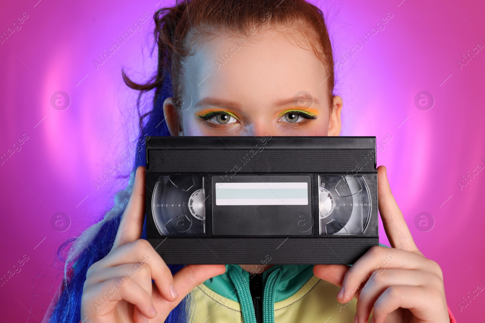 Photo of Cute indie girl with VHS cassette on violet background