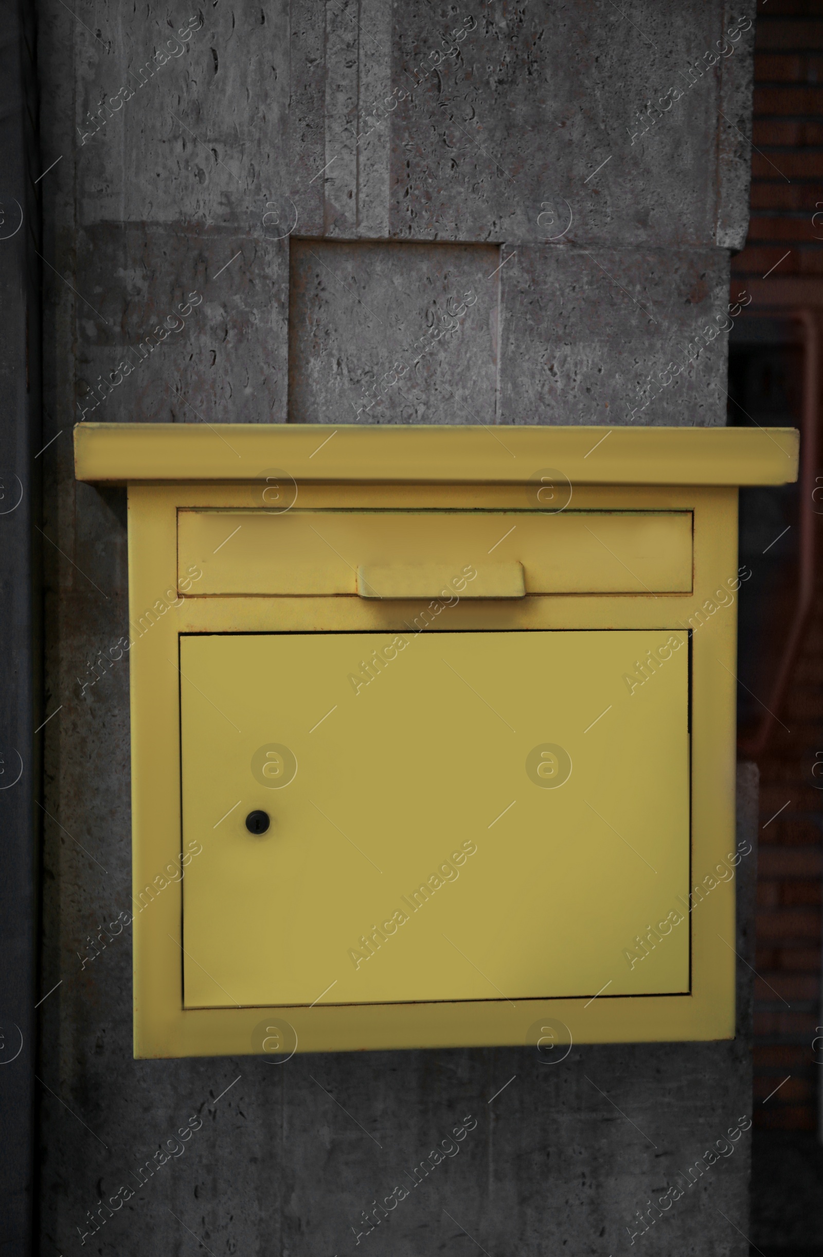 Photo of Yellow metal letter box on wall outdoors