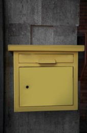 Yellow metal letter box on wall outdoors