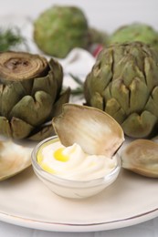 Delicious cooked artichokes with tasty sauce served on plate, closeup