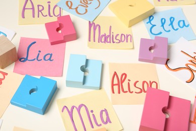 Colorful paper sheets with written different baby names and toys on beige background