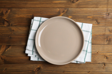 Photo of Empty plate and napkin on wooden table, top view