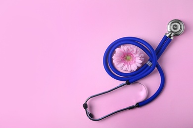 Photo of Flat lay composition with stethoscope and flower on pink background, space for text. Gynecology concept