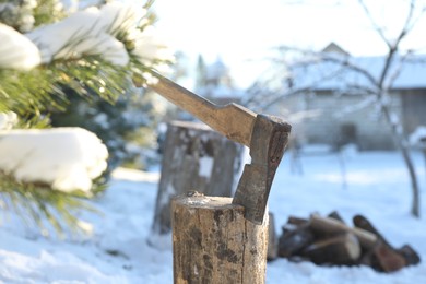 Metal axe in wooden log outdoors on sunny winter day