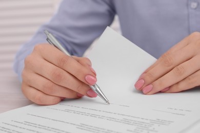 Woman signing document at table, closeup view
