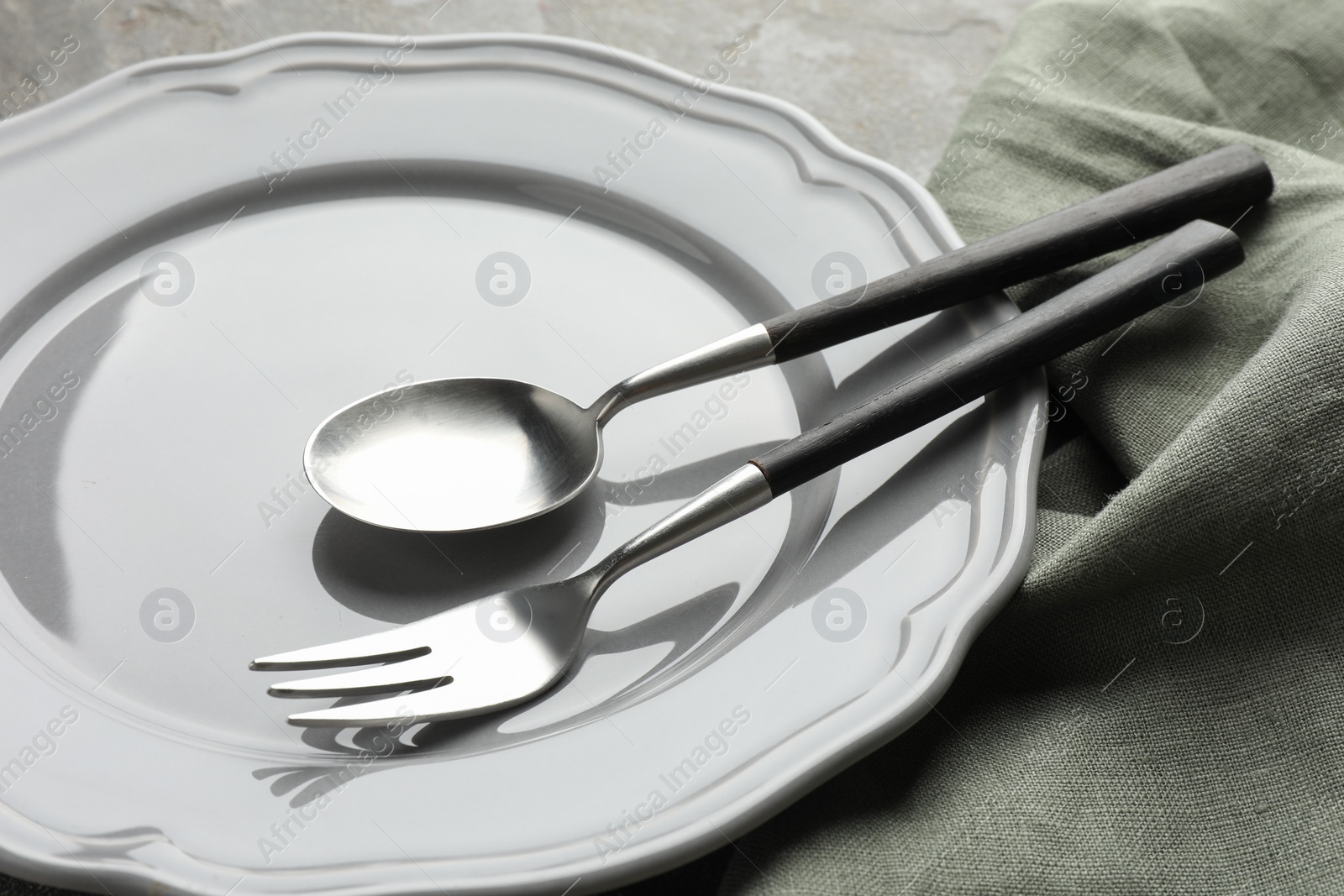 Photo of Stylish setting with cutlery, napkin and plate on table, closeup