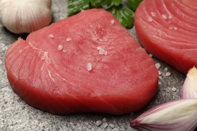 Photo of Raw tuna fillets with salt and shallot on gray table, closeup
