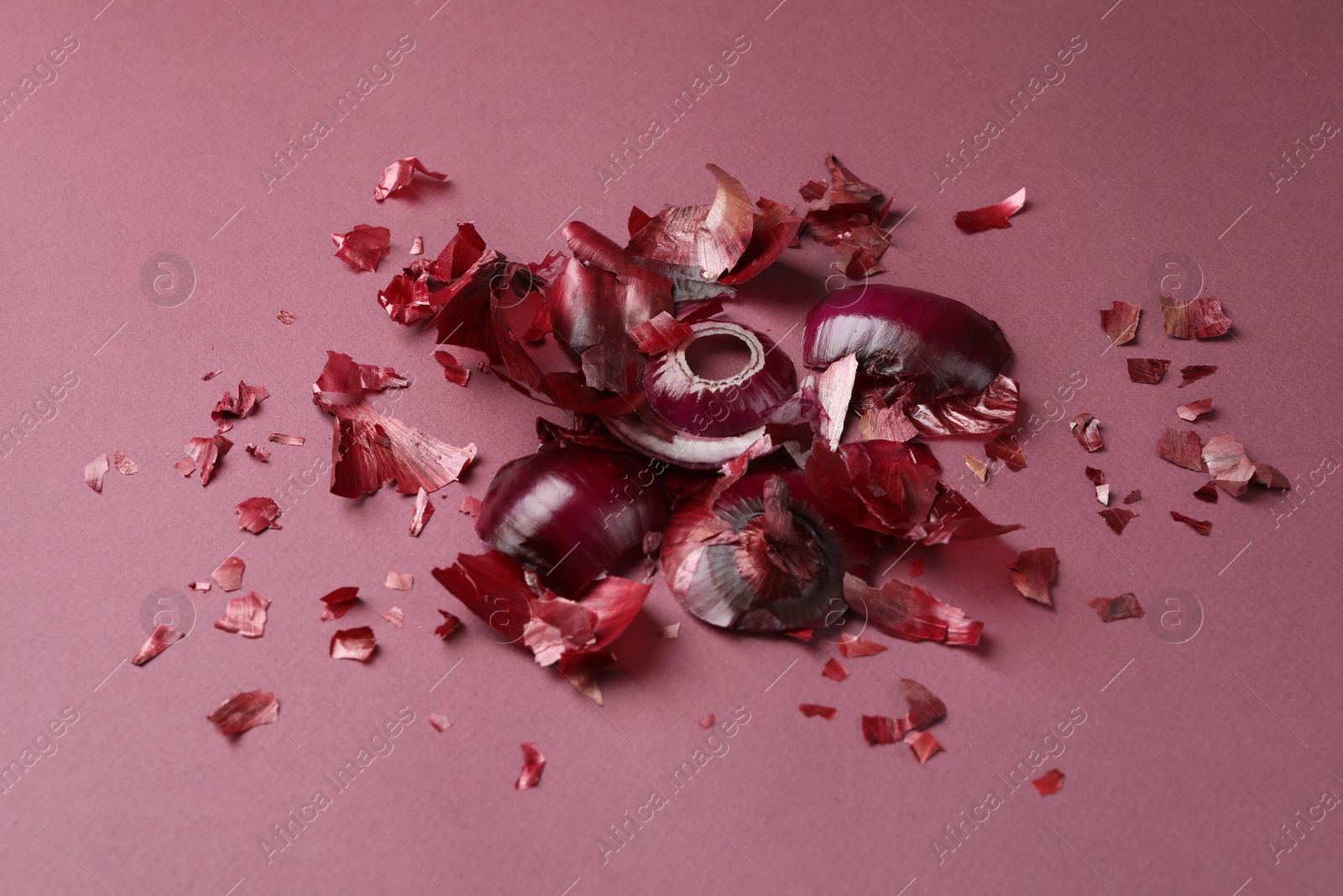 Photo of Peels of fresh red onion on dark pink background