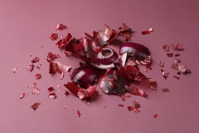 Peels of fresh red onion on dark pink background