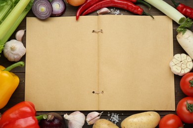 Blank recipe book surrounded by different ingredients on wooden table, flat lay. Space for text