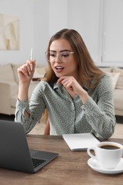 Photo of Beautiful woman with laptop at wooden table in room