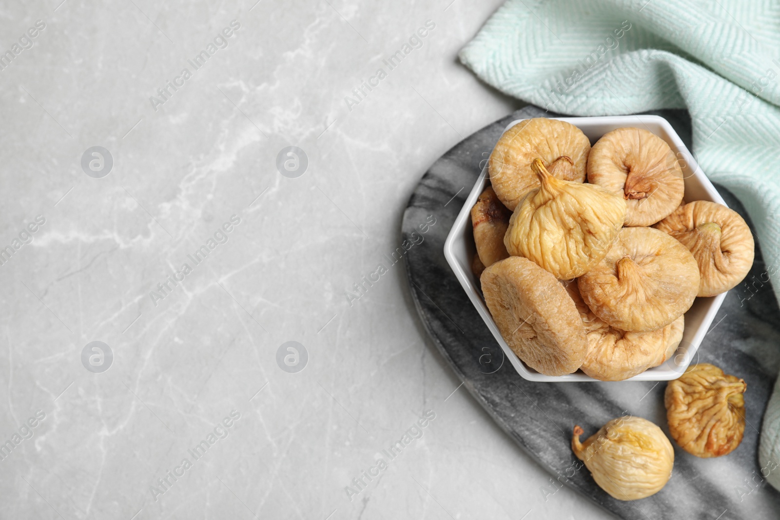 Photo of Tasty dried figs in bowl on light grey table, top view. Space for text