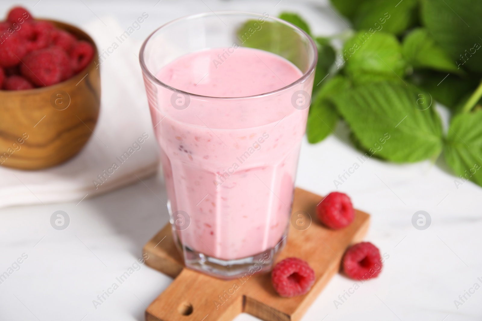 Photo of Tasty raspberry smoothie in glass on white table, closeup