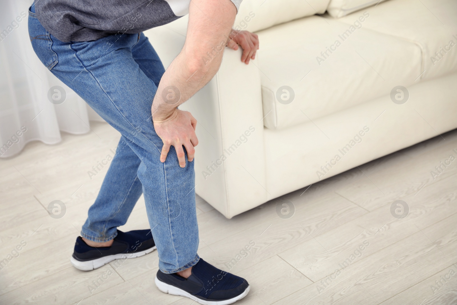 Photo of Young man suffering from leg pain indoors, closeup. Space for text