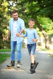 Photo of Father and son roller skating in summer park