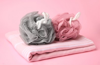 Colorful shower puffs and towel on pink background