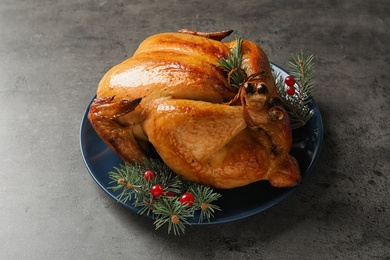 Photo of Platter of cooked turkey with cranberry and fir tree branches on grey background