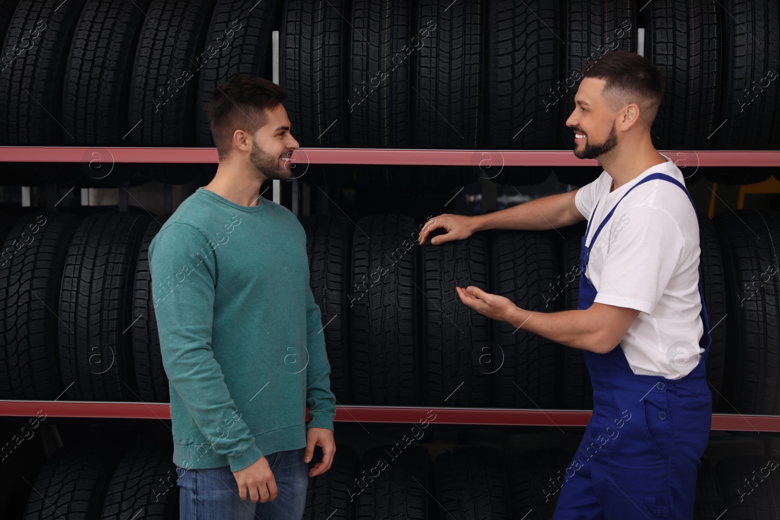 Photo of Mechanic helping client to choose car tire in auto store