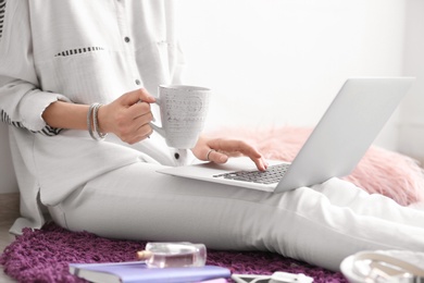 Female blogger with laptop and cup of coffee indoors