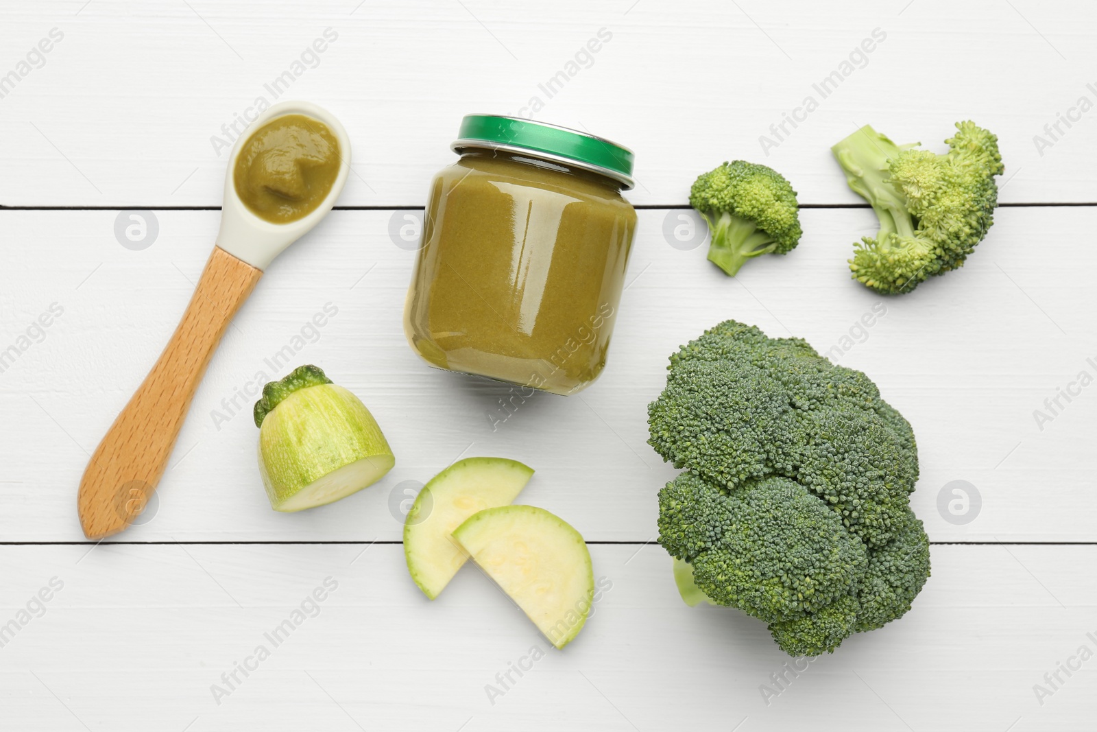 Photo of Tasty baby food in jar, broccoli and zucchini on white wooden table, flat lay