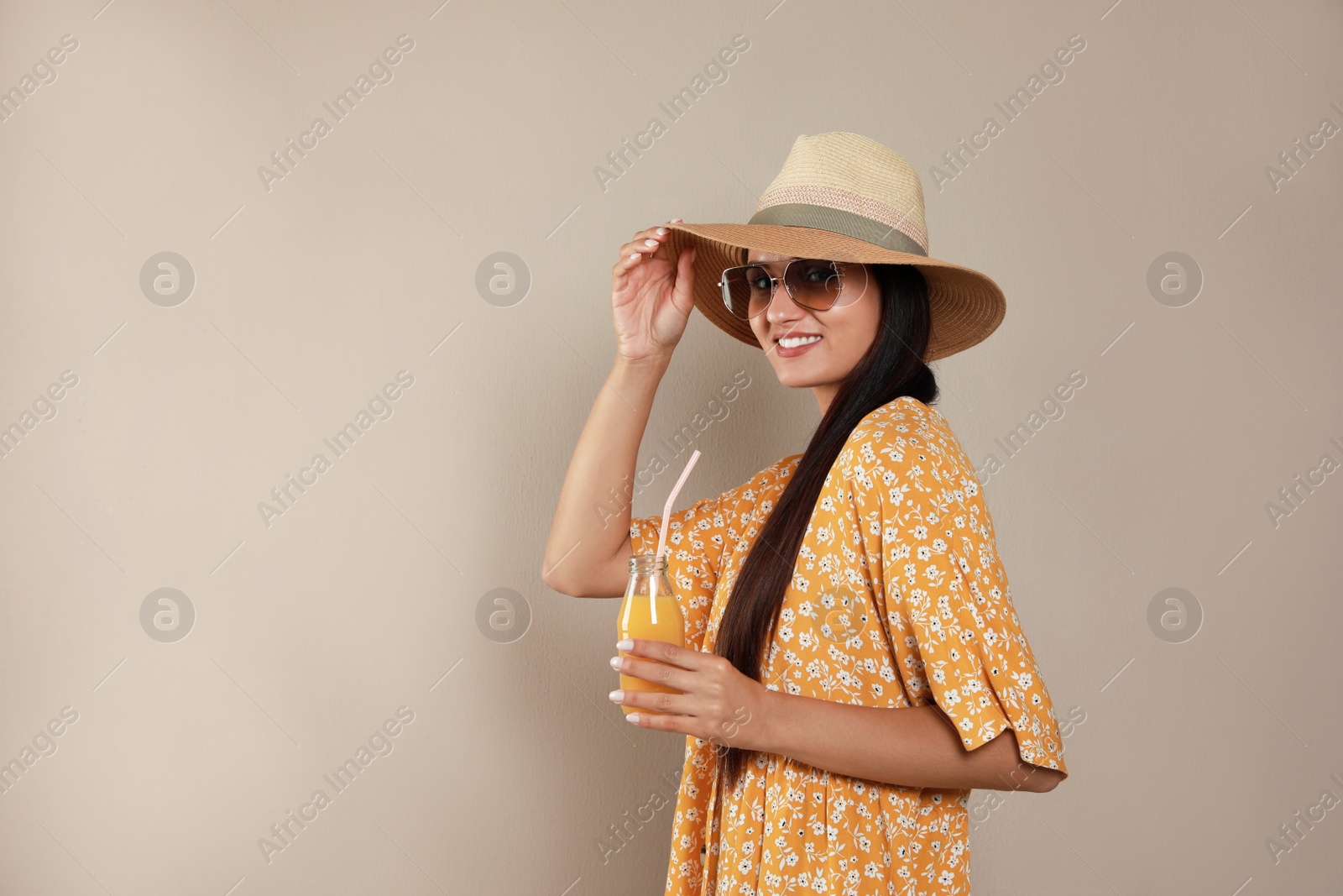 Photo of Beautiful young woman with straw hat and glass of refreshing drink on beige background. Space for text