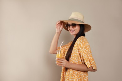 Photo of Beautiful young woman with straw hat and glass of refreshing drink on beige background. Space for text