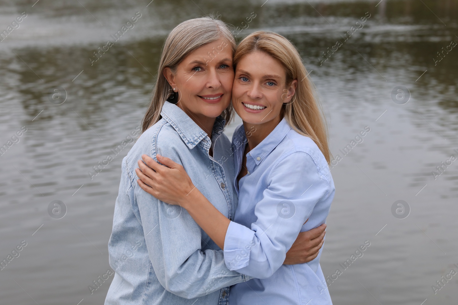 Photo of Happy mature mother and her daughter hugging near pond