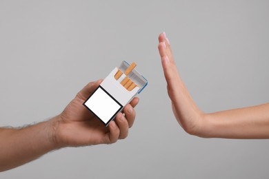 Photo of Stop smoking concept. Woman refusing cigarettes on grey background, closeup