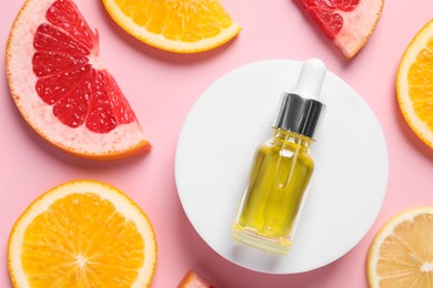 Photo of Bottle of cosmetic serum and citrus fruit slices on pink background, flat lay