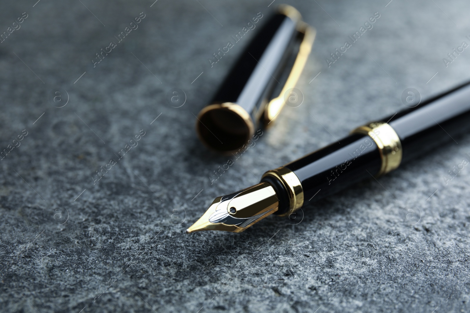 Photo of Beautiful fountain pen with ornate nib on grey table, closeup. Space for text