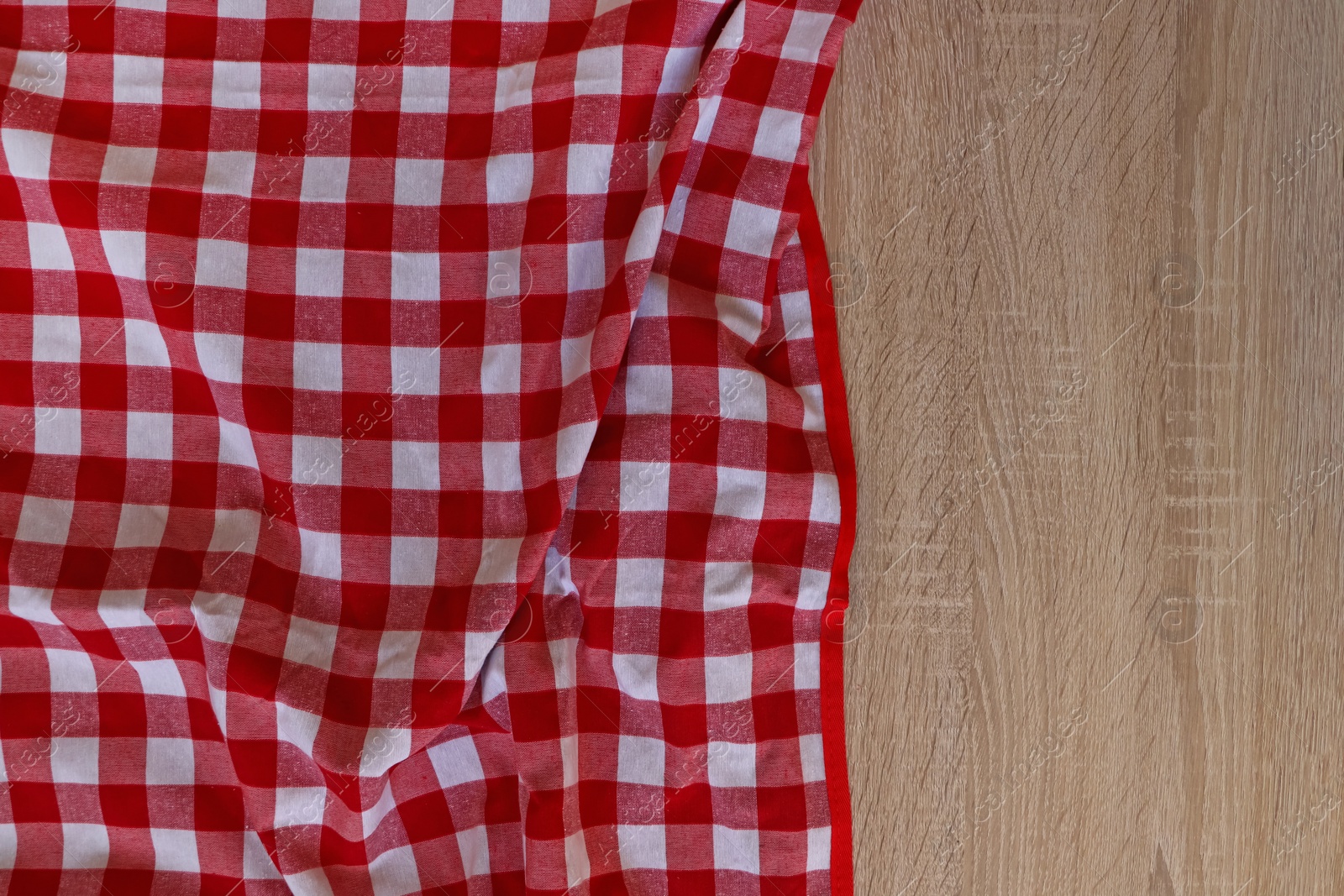 Photo of Checkered picnic cloth on wooden table, top view. Space for text