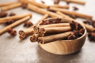 Photo of Aromatic cinnamon sticks and anise on grey marble table, closeup