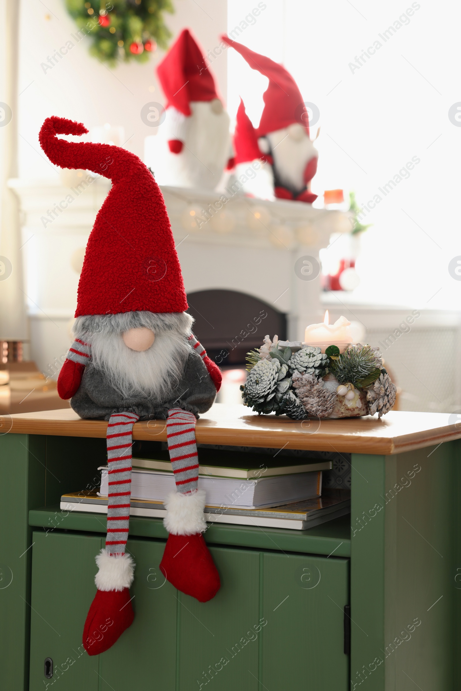 Photo of Cute Christmas gnome on wooden table in room with festive decorations