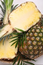 Photo of Whole and cut ripe pineapples on white wooden table, top view