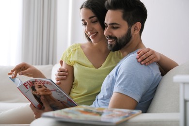 Photo of Young couple reading sports magazine on sofa at home