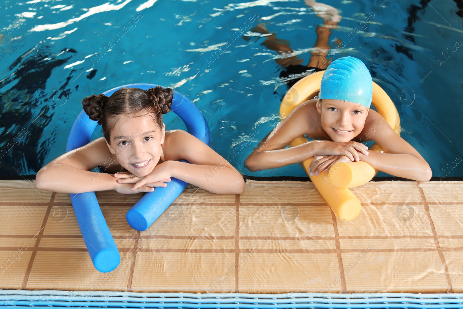 Photo of Little kids with swimming noodles in indoor pool