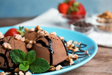 Plate of chocolate ice cream with nuts on wooden table, closeup. Space for text