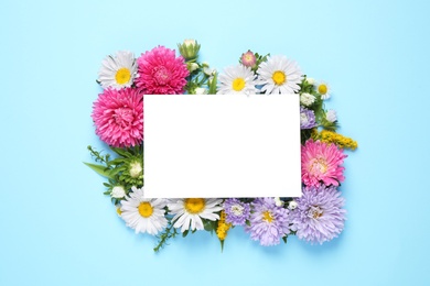 Flat lay composition with beautiful aster flowers and blank card on light blue background. Space for text