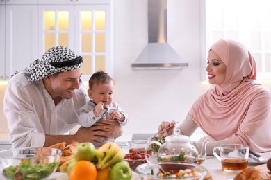 Photo of Happy Muslim family with little son at served table in kitchen