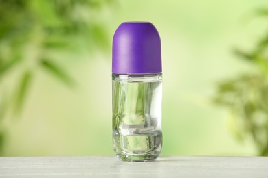 Photo of Deodorant container on white wooden table against blurred background