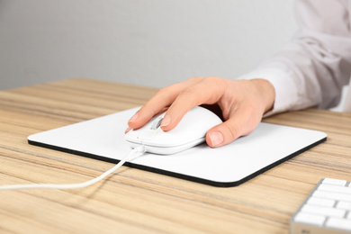 Photo of Woman using modern wired optical mouse at office table, closeup