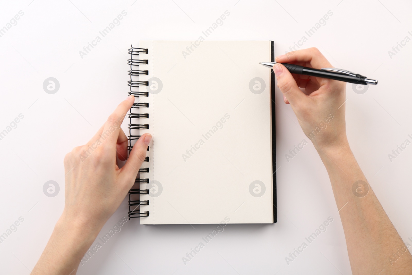 Photo of Woman writing in notebook on white background, top view