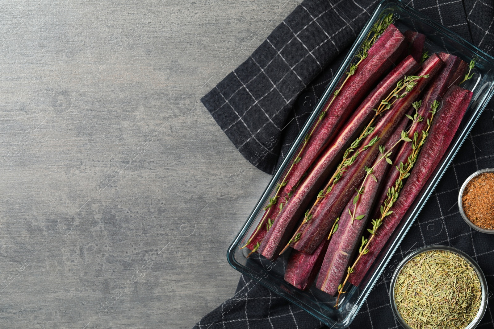 Photo of Flat lay composition with raw cut black carrot in  baking dish on grey table. Space for text