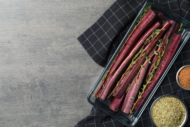 Flat lay composition with raw cut black carrot in  baking dish on grey table. Space for text