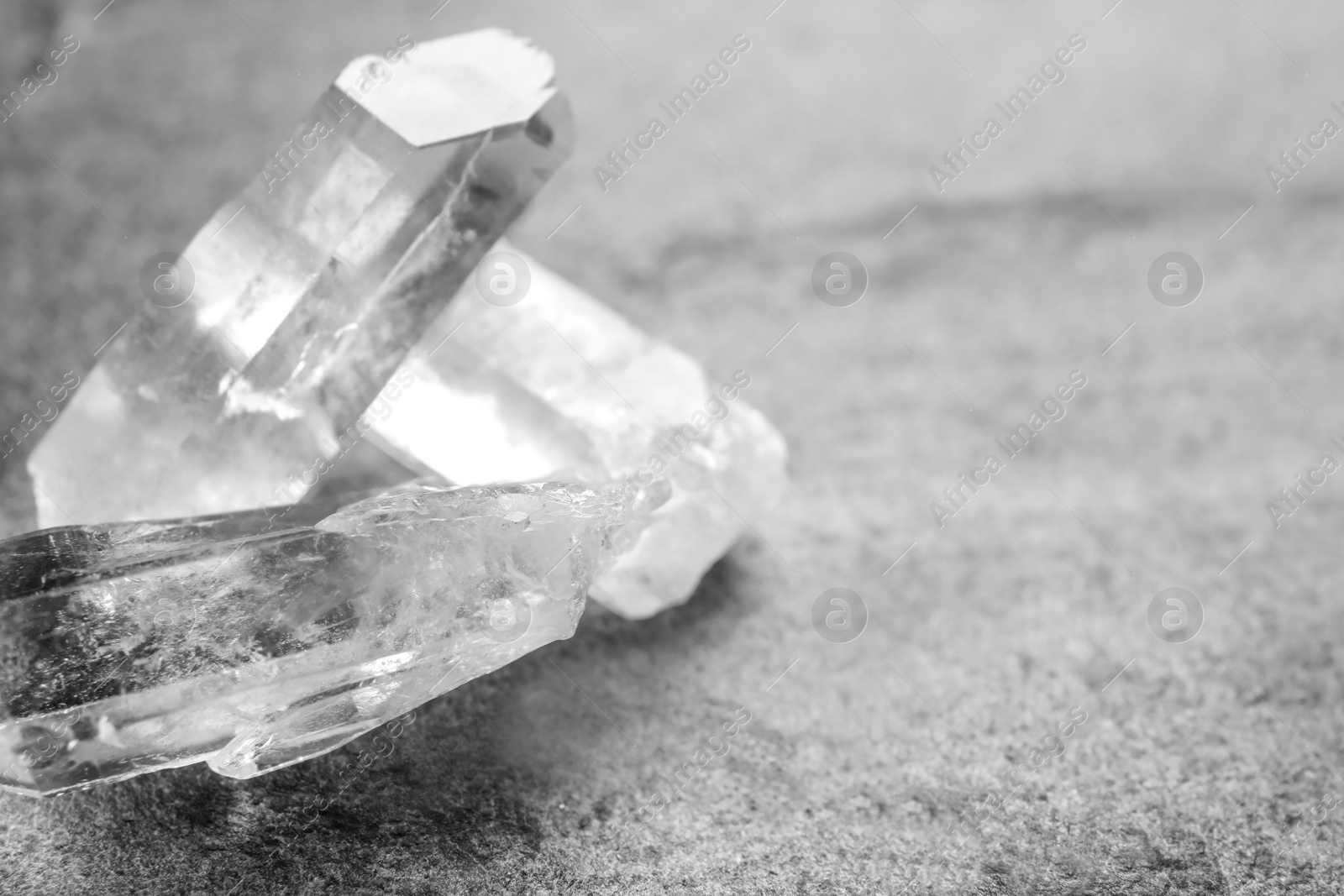 Photo of Beautiful rock crystal gemstones on grey table, space for text