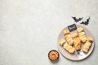 Photo of Spooky sausage mummies for Halloween party served on light grey table, flat lay. Space for text