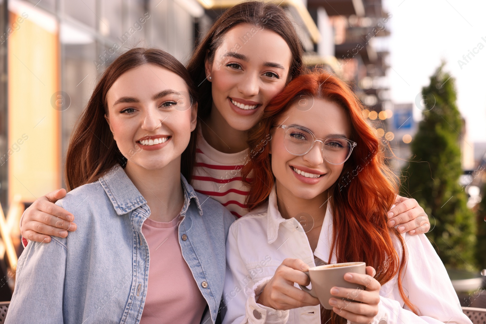 Photo of Happy friends drinking coffee in outdoor cafe