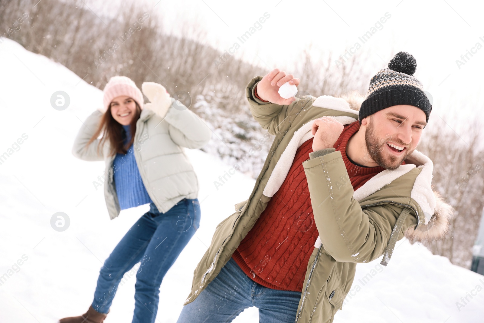 Photo of Happy couple playing snowballs outdoors. Winter vacation