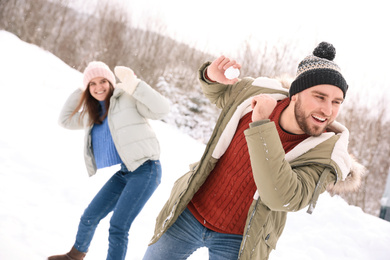 Photo of Happy couple playing snowballs outdoors. Winter vacation