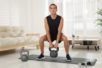 Photo of Handsome man training with kettlebell at home